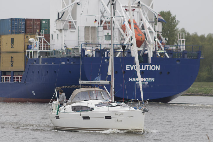 Segler und Frachtschiff im Kanal