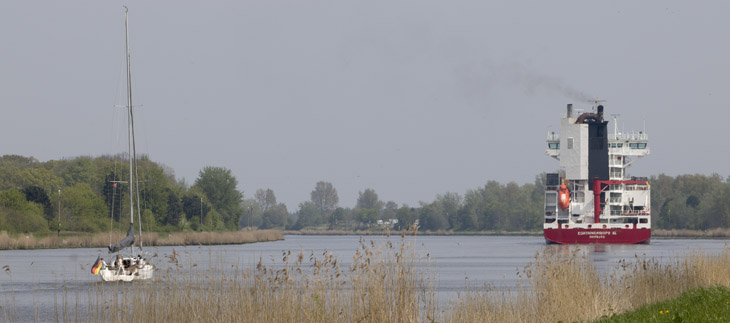 Segler und Frachter im Kanal